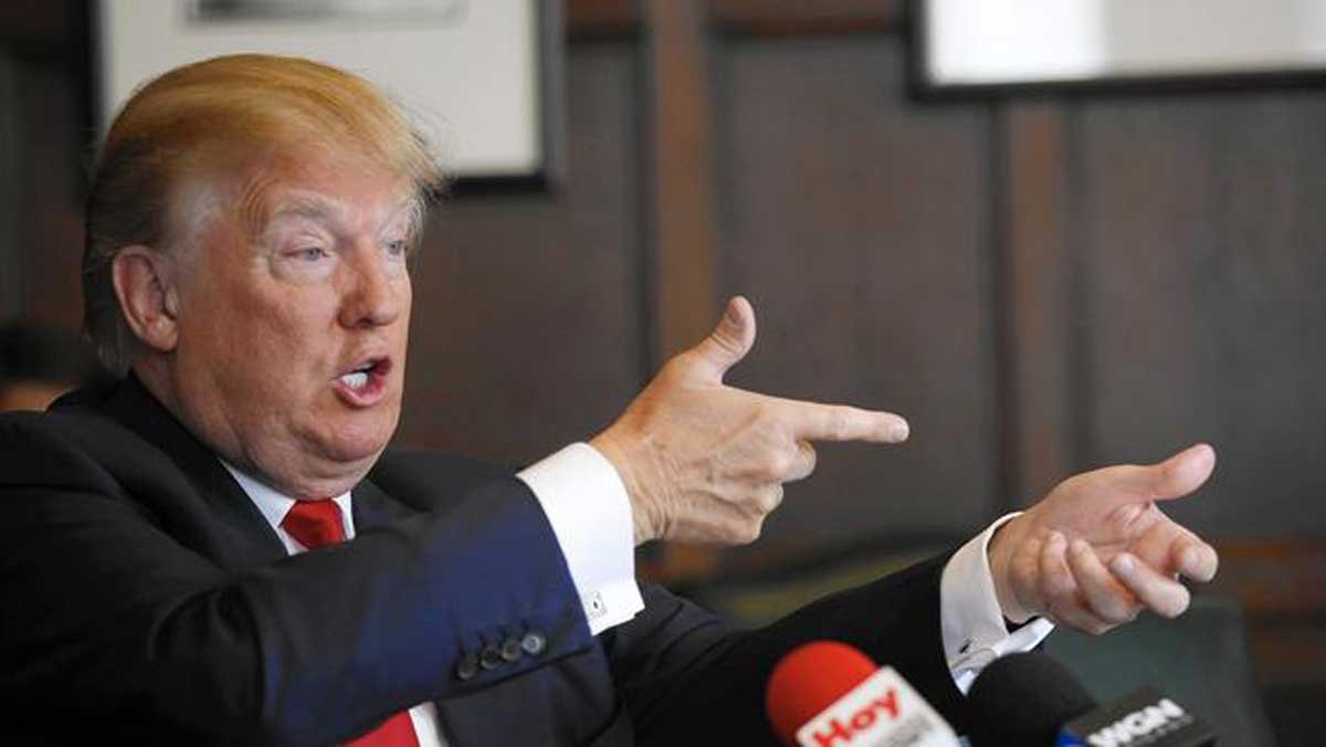 Trump fa il gesto di sparare vestito in giacca e cravatta rossa